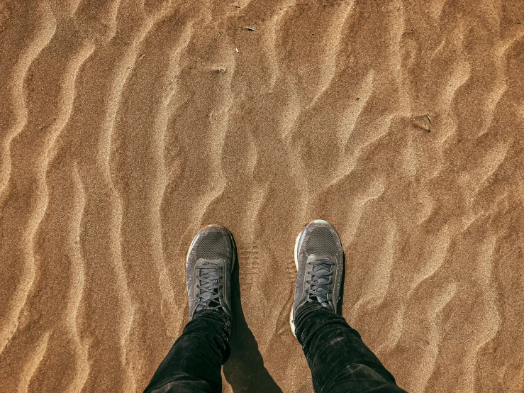 a person standing on top of a sandy beach, trending on pexels, realism, sneaker, desert of distortion, wet floors, my pov