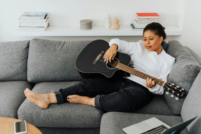 a woman sitting on a couch playing a guitar, pexels contest winner, guitar shape build, ashteroth, sydney hanson, madeline from celeste