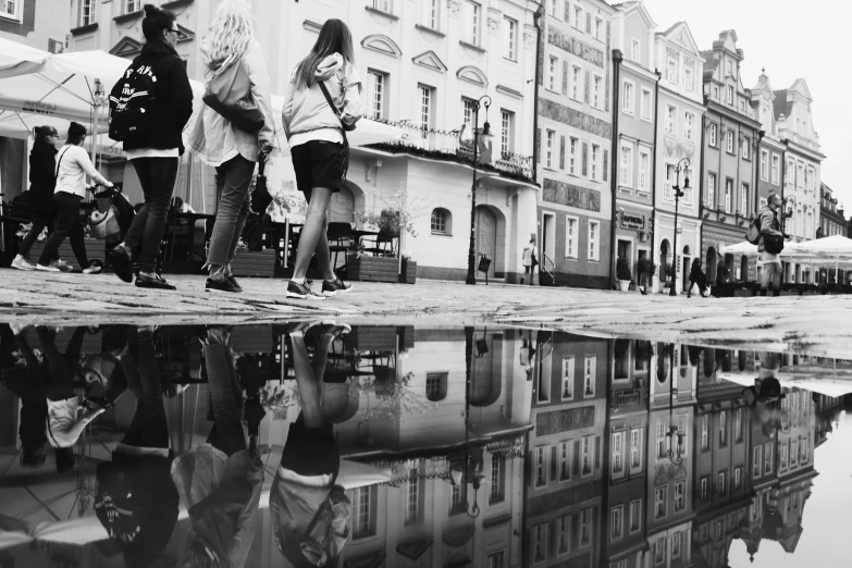 a group of people walking down a street with umbrellas, a black and white photo, by Emma Andijewska, pexels, street art, water mirrored water, russian city, after rain and no girls, water reflection on the floor