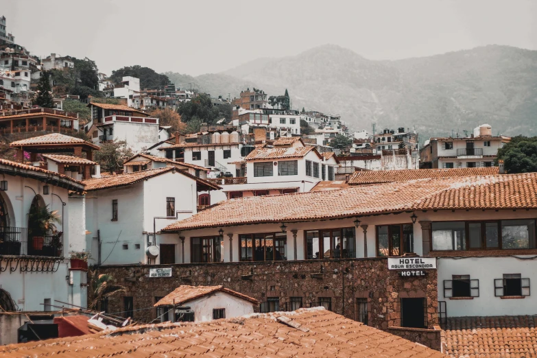 a view of a town with a mountain in the background, by Alejandro Obregón, pexels contest winner, tiled roofs, background image, white building, brown