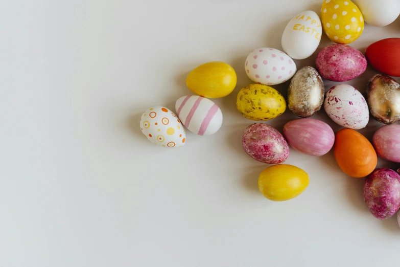 a white table topped with lots of different colored eggs, pexels contest winner, pink and yellow, 5k, patterned, pebbles