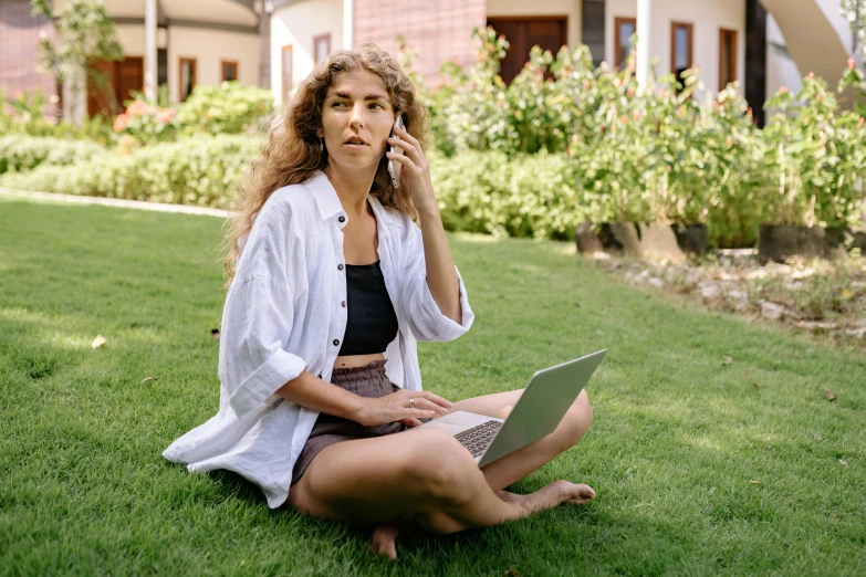 a woman sitting on the grass talking on a cell phone, by Julia Pishtar, trending on pexels, happening, sitting at a computer, slightly tanned, curly haired, annoyed