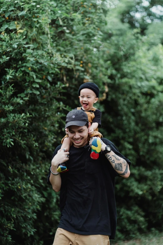 a man carrying a child on his shoulders, inspired by Eddie Mendoza, unsplash, mac miller, in garden, wearing a backwards baseball cap, pitbull