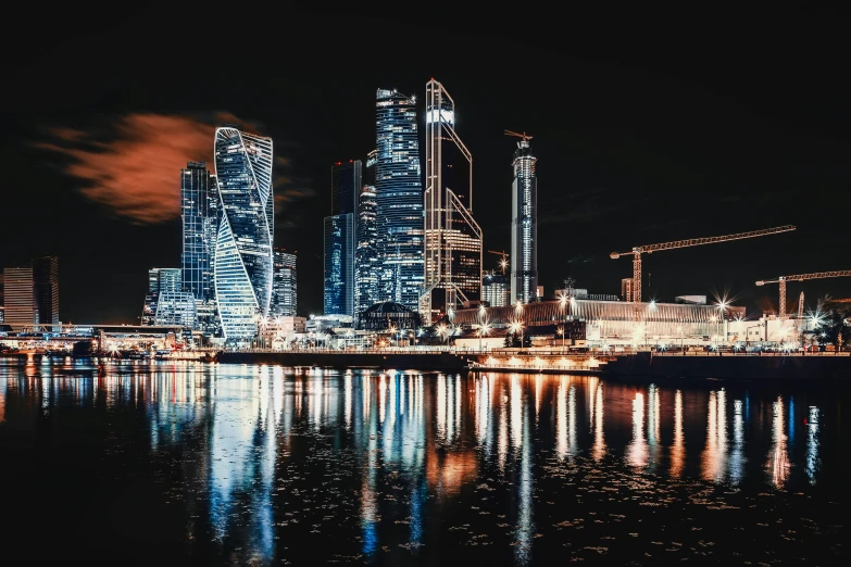 a city at night with lights reflecting in the water, by Julia Pishtar, pexels contest winner, russian constructivism, skyline showing, instagram post, with shiny glass buildings