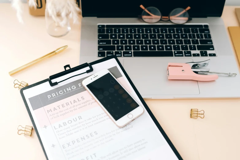 a clipboard sitting on top of a desk next to a laptop, by Julia Pishtar, 9 9 designs, professional iphone photo, thumbnail, brown and pink color scheme