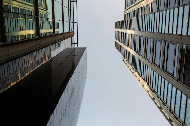 a couple of tall buildings next to each other, a picture, inspired by Richard Wilson, pexels contest winner, minimalism, high vantage point, looking upwards, a medium shot, foster and partners