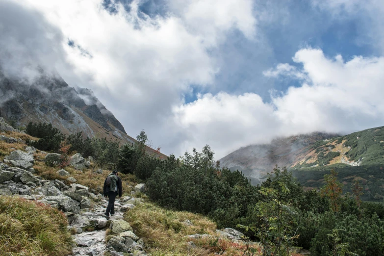 a person walking up a rocky path in the mountains, upon the clouds, avatar image, conde nast traveler photo