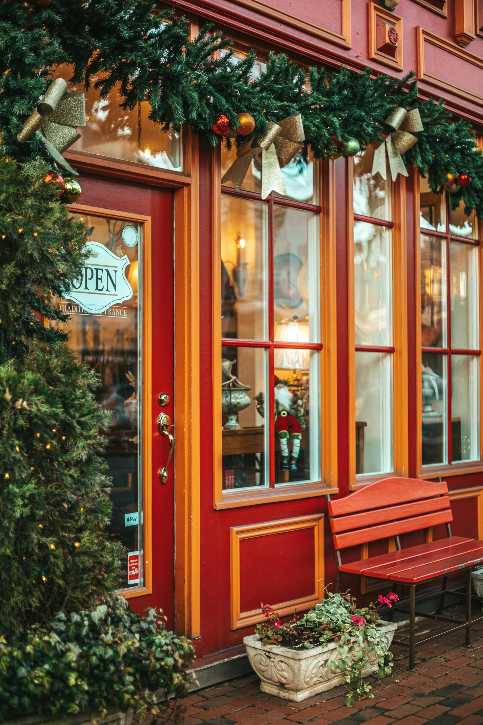 a couple of benches sitting in front of a building, decorated ornaments, french door window, warmly lit, storefront