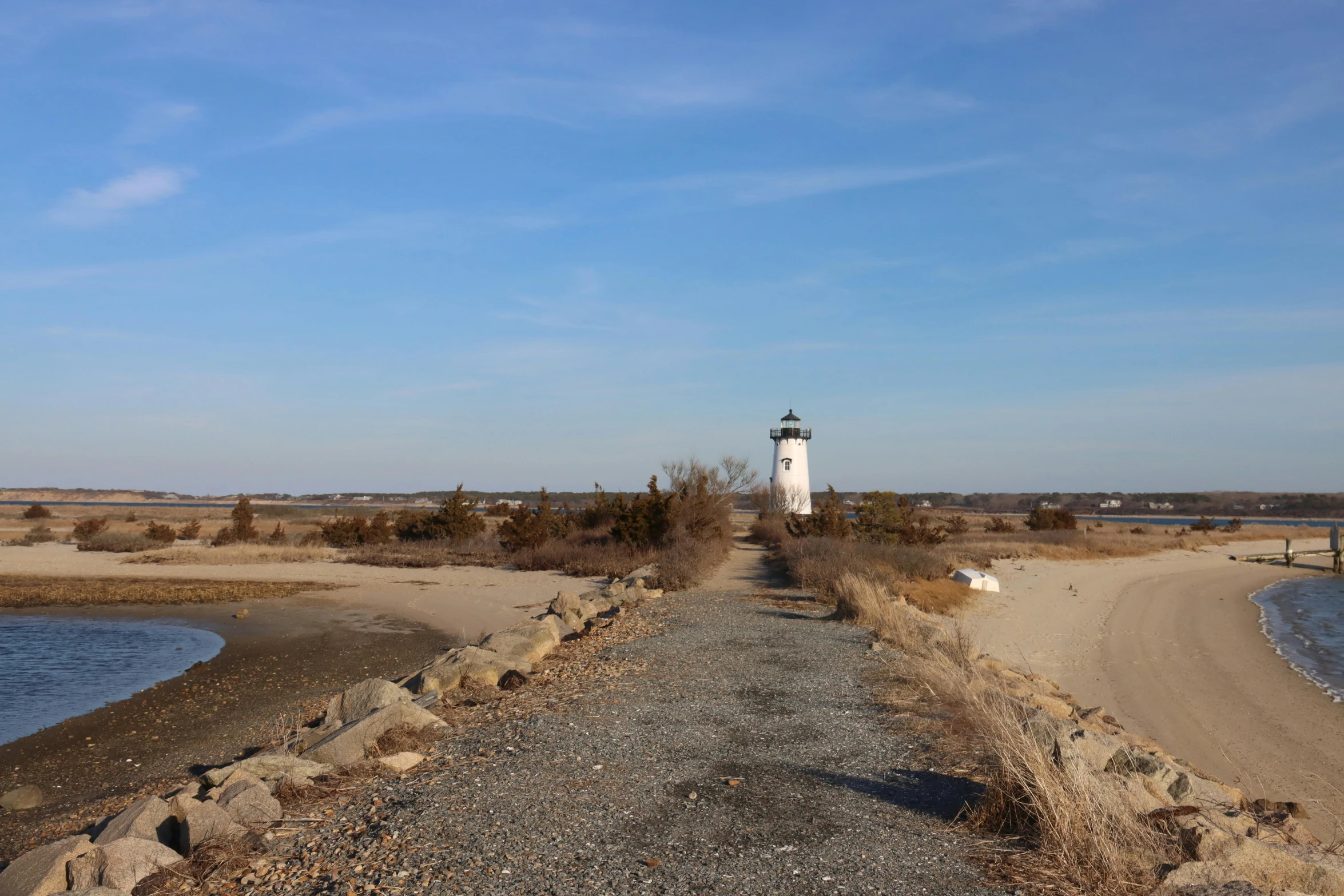 a lighthouse sitting on top of a sandy beach next to a body of water, by Ryan Pancoast, land art, a road leading to the lighthouse, upon a peak in darien, maintenance photo, woo kim