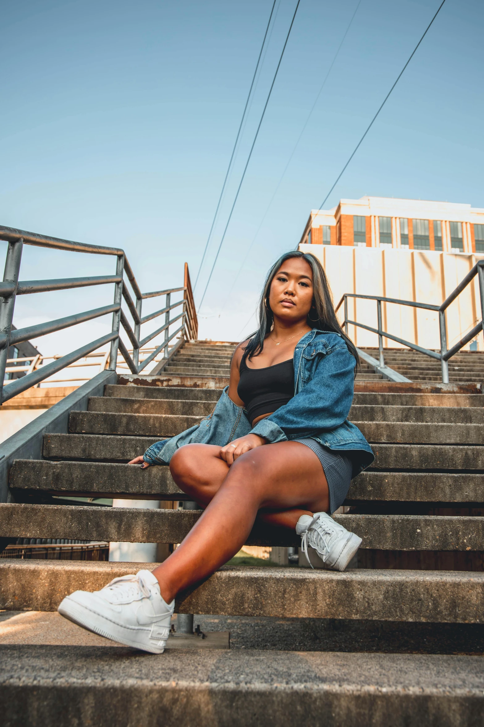 a woman sitting on a set of stairs, trending on unsplash, tan skin a tee shirt and shorts, shot on sony a 7, high school, bright sky