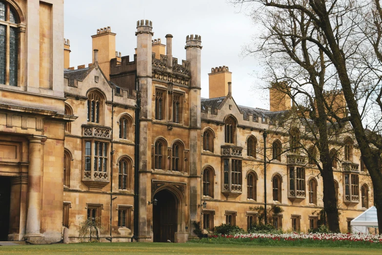 a large building sitting on top of a lush green field, inspired by Sydney Prior Hall, renaissance, neo - gothic architecture, courtyard walkway, golden windows, aged 2 5