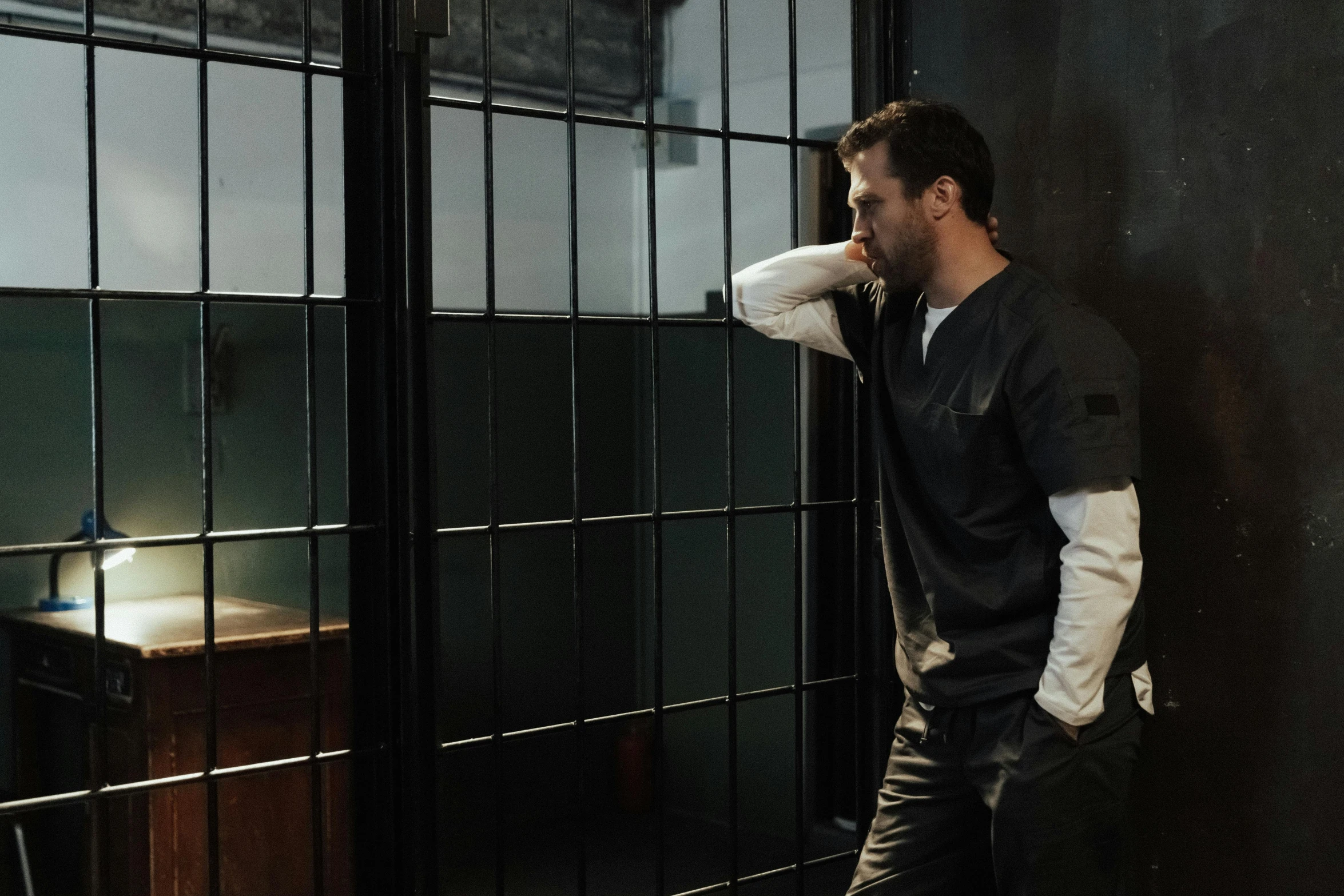 a man leaning against a wall in a jail cell, inspired by Joseph Morgan Henninger, pexels contest winner, serial art, charlie day, doctor house, background image, perfectly lit. movie still