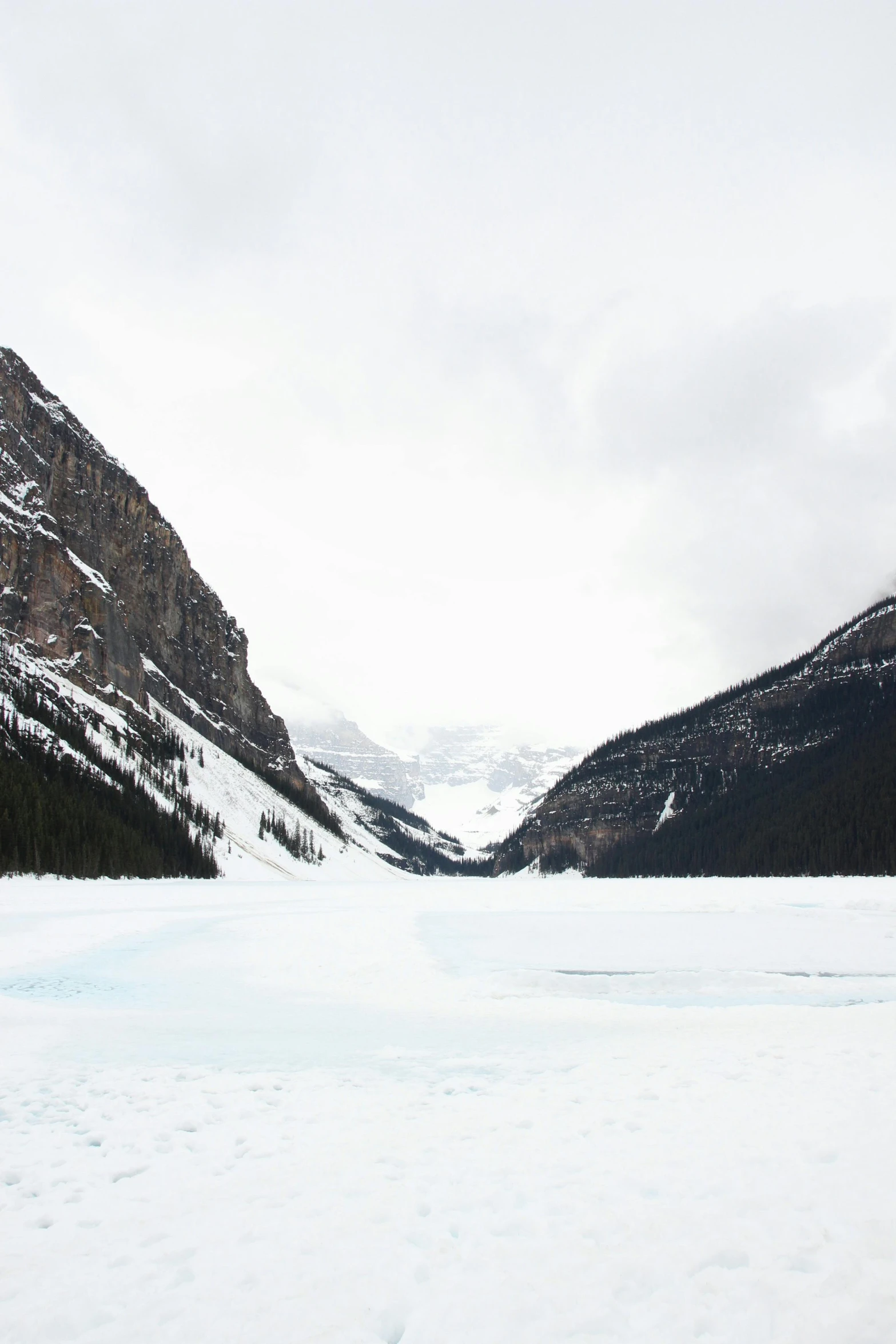 a man riding skis down a snow covered slope, a photo, inspired by James Pittendrigh MacGillivray, pexels contest winner, lake in foreground, slightly minimal, banff national park, frozen like a statue