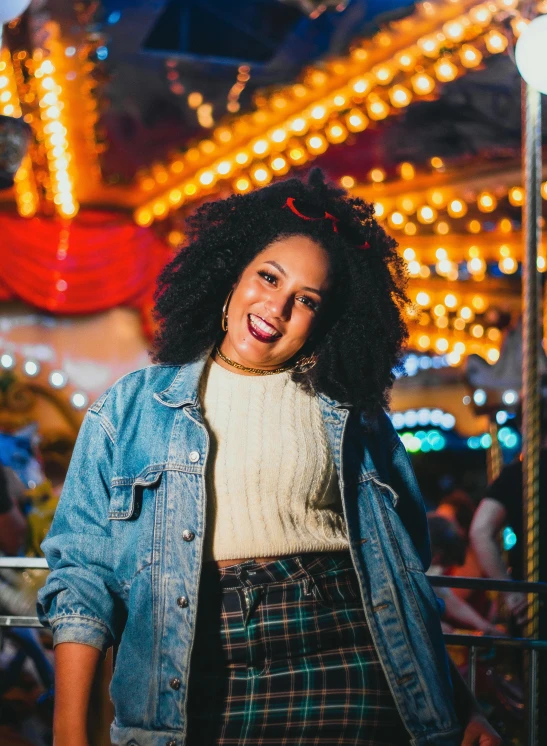 a woman standing in front of a carousel at night, a portrait, by Winona Nelson, pexels contest winner, dark short curly hair smiling, female streetwear blogger, lizzo, bright daylight