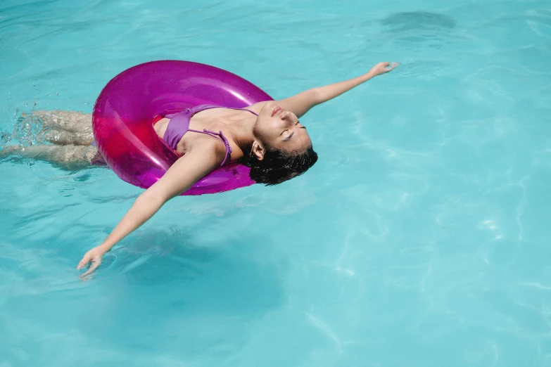 a woman floating on an inner tube in a pool, pexels contest winner, arms stretched out, 15081959 21121991 01012000 4k, purple water, no watermark