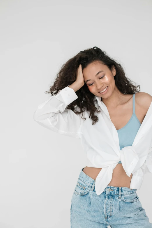 a woman in a white shirt and blue jeans, trending on unsplash, curls on top, happy fashion model, bella poarch, promo image