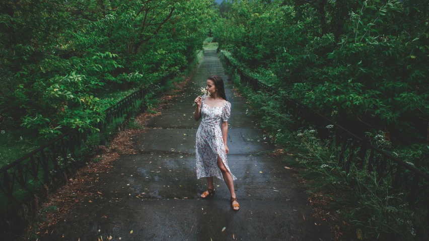 a woman walking down a path through a lush green forest, inspired by Elsa Bleda, pexels contest winner, renaissance, pretty girl standing in the rain, drinking, wearing heels and white dress, wearing a long flowery dress