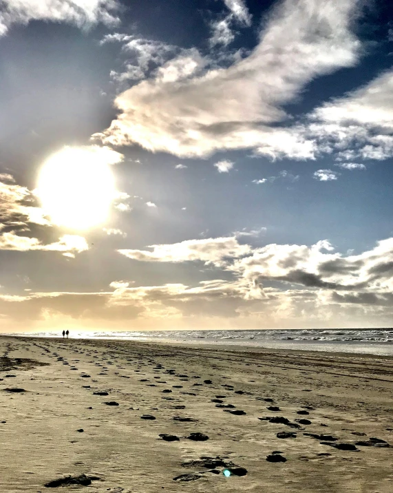 a man flying a kite on top of a sandy beach, by Jan Tengnagel, happening, footprints in the sand, with two suns in the sky, trending photo, walking to the right