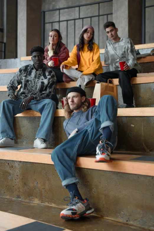 a group of people sitting on the steps of a building, by Lee Gatch, trending on pexels, photorealism, baggy jeans, the last portrait of mac miller, sitting on a mocha-colored table, promotional image