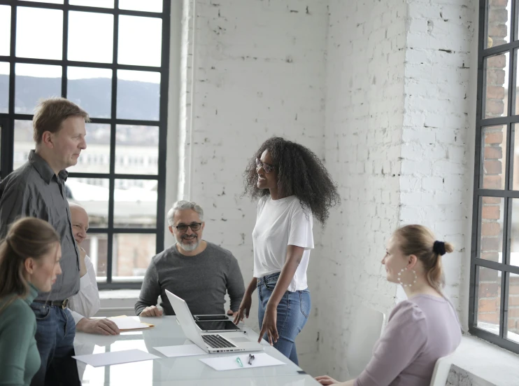 a group of people standing around a table, in an office, profile image