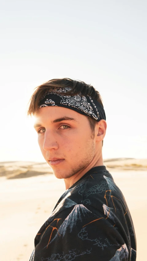 a man standing on top of a sandy beach, black bandana mask, symmetrical face orelsan, profile image, thumbnail