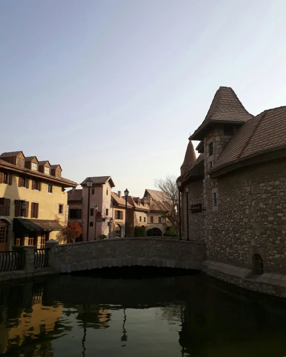 a bridge over a body of water with buildings in the background, renaissance, french village exterior, instagram picture, qiangshu, amusement park buildings