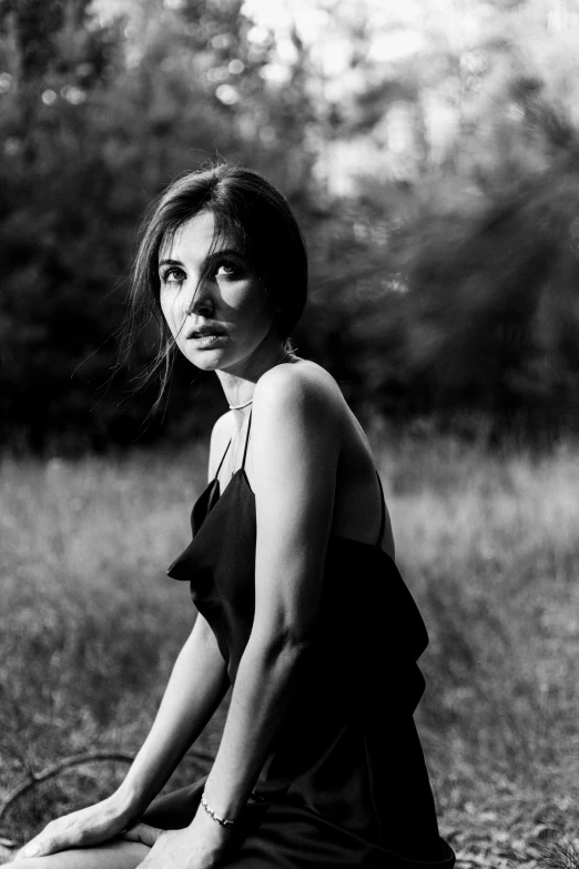 a black and white photo of a woman sitting in a field, by Tamas Galambos, portrait of ana de armas, ((portrait)), evening sun, egor letov