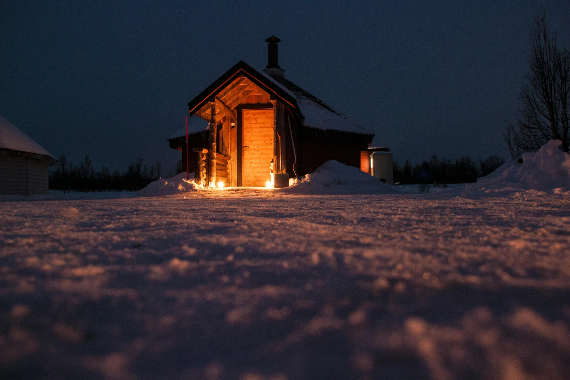 a small cabin lit up at night in the snow, a portrait, inspired by Einar Hakonarson, pexels contest winner, land art, volumetric evening lights, full body in shot, ready to eat, grey