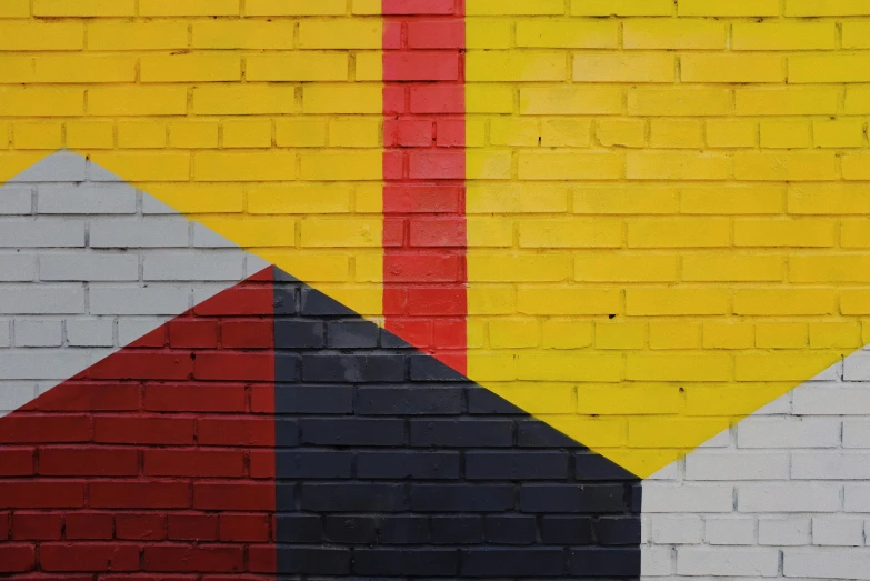 a fire hydrant sitting in front of a brick wall, inspired by Bauhaus, pexels contest winner, geometric abstract art, red yellow black, wall mural, colors: yellow, conor walton