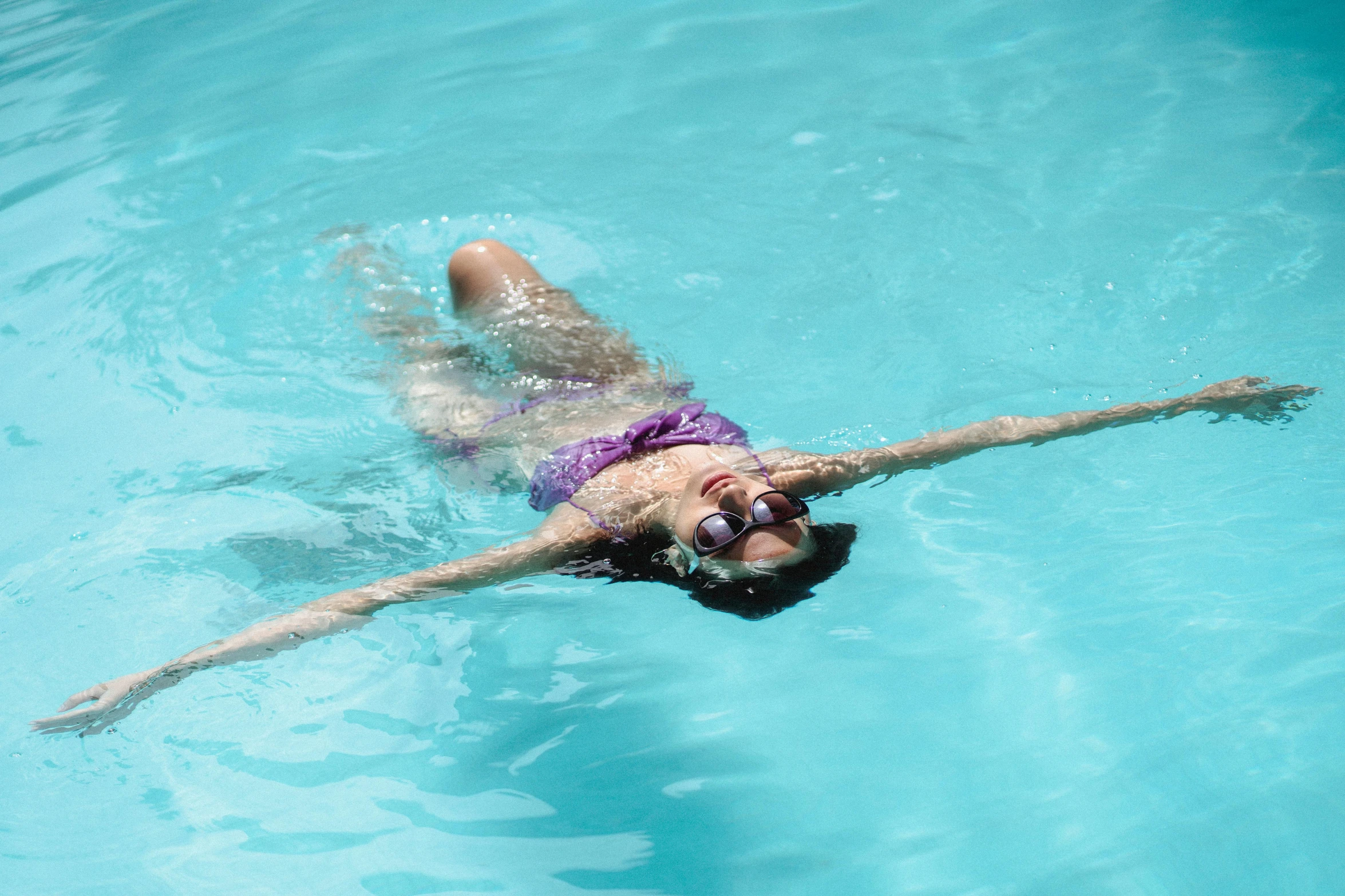 a woman in a purple bikini swims in a pool, pexels contest winner, arms stretched out, wearing goggles, profile image, maintenance