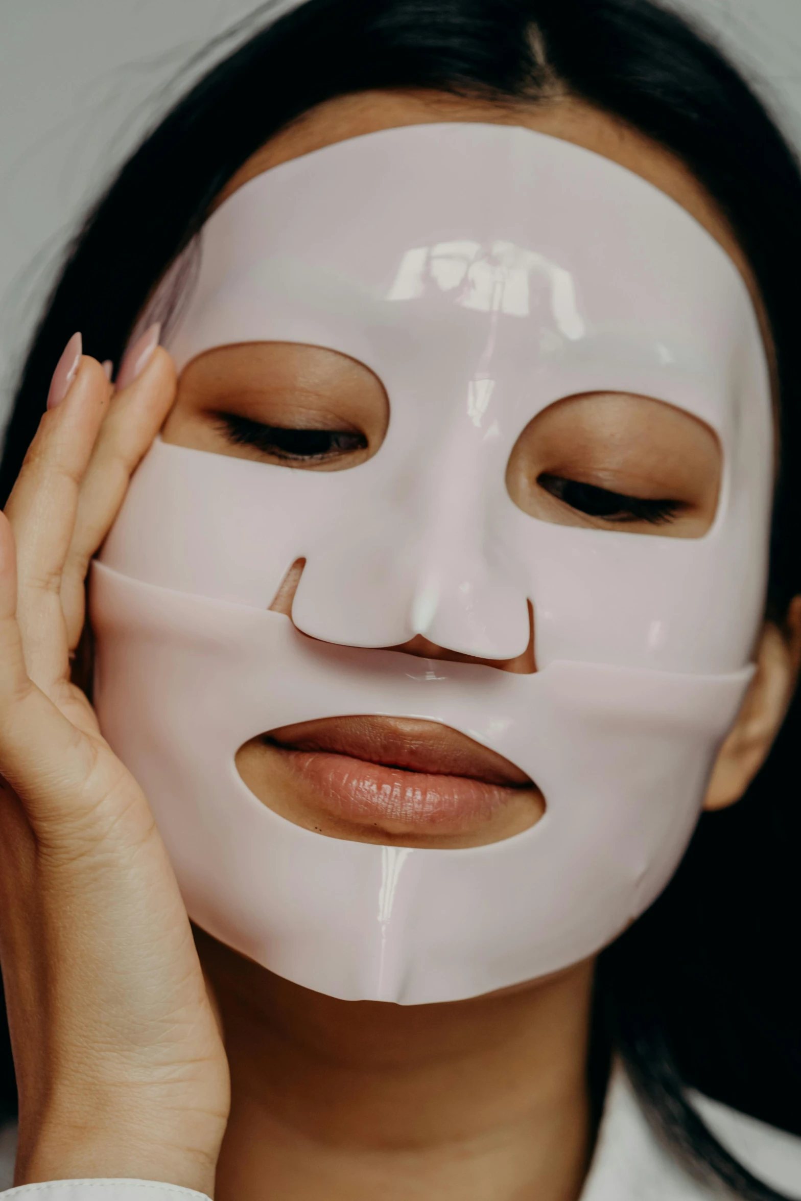 a woman with a sheet mask on her face, face centred, silicone skin, asian features, front lit