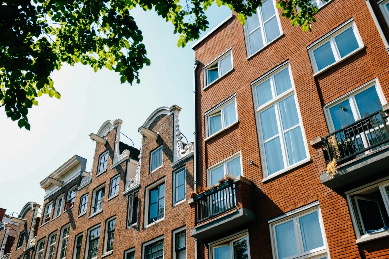 a red brick building with many windows and balconies, a photo, by Jan Tengnagel, pexels, view of houses in amsterdam, view from the ground, summer light, van lieven