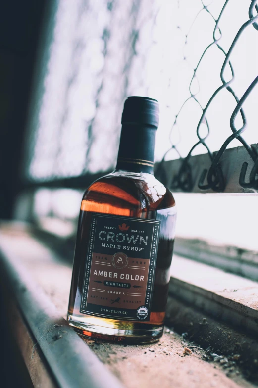 a bottle of whiskey sitting on a window sill, by Matt Cavotta, instagram contest winner, private press, resembling a crown, maple syrup, black and brown colors, thumbnail