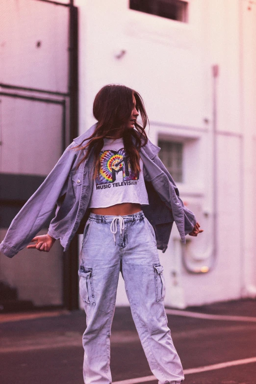 a woman riding a skateboard down a street, a colorized photo, inspired by Elsa Bleda, trending on pexels, graffiti, cropped shirt with jacket, doing a sassy pose, with ripped crop t - shirt, 8 0 - s fashion