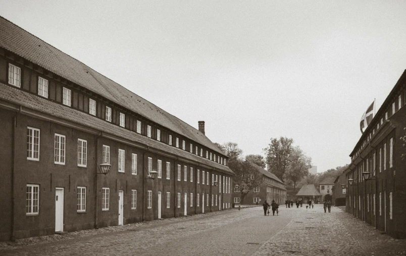 a black and white photo of people walking down a street, inspired by August Sander, unsplash, barbizon school, barracks, lower saxony, old color photograph, of augean stables