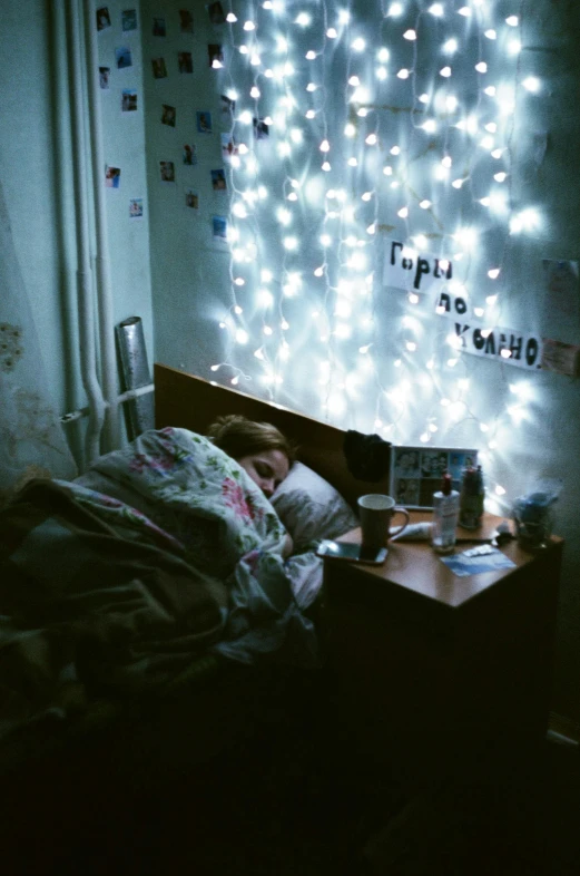 a person laying in a bed under a string of lights, a picture, inspired by Elsa Bleda, tumblr, happening, 'i'm so tired, phot