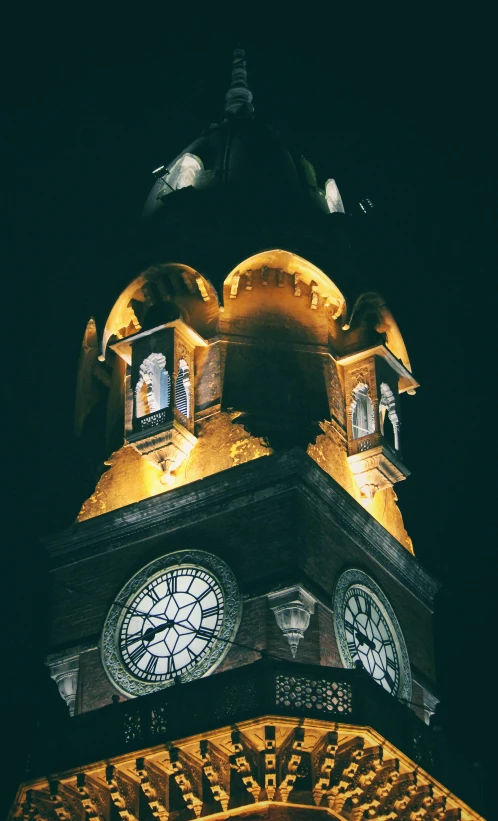 a large clock tower lit up at night, inspired by Christopher Wren, romanesque, low quality photo, low-light photograph, marilyn church h, low angle photo