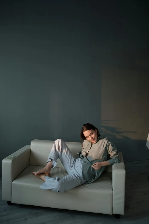 a man laying on a couch next to a lamp, inspired by Elsa Bleda, trending on pexels, pale blue outfit, portrait androgynous girl, full body pose, gray canvas