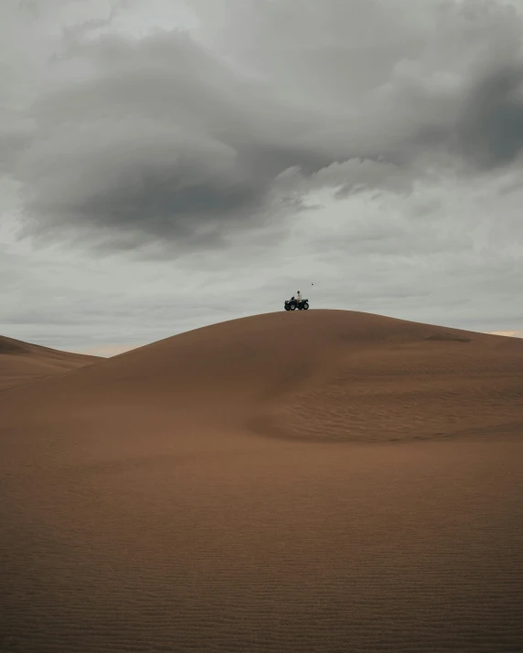 a truck driving across a desert under a cloudy sky, by Daniel Seghers, unsplash contest winner, the wise man is riding on top, victorian arcs of sand, house on a hill, overcast gray skies