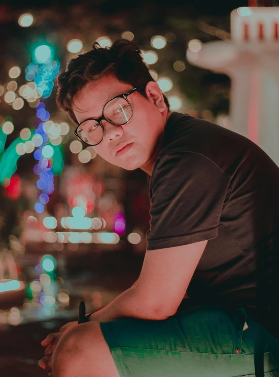 a man sitting on top of a green fire hydrant, an album cover, by Robbie Trevino, pexels contest winner, wearing square glasses, christmas night, profile image, he is about 20 years old | short