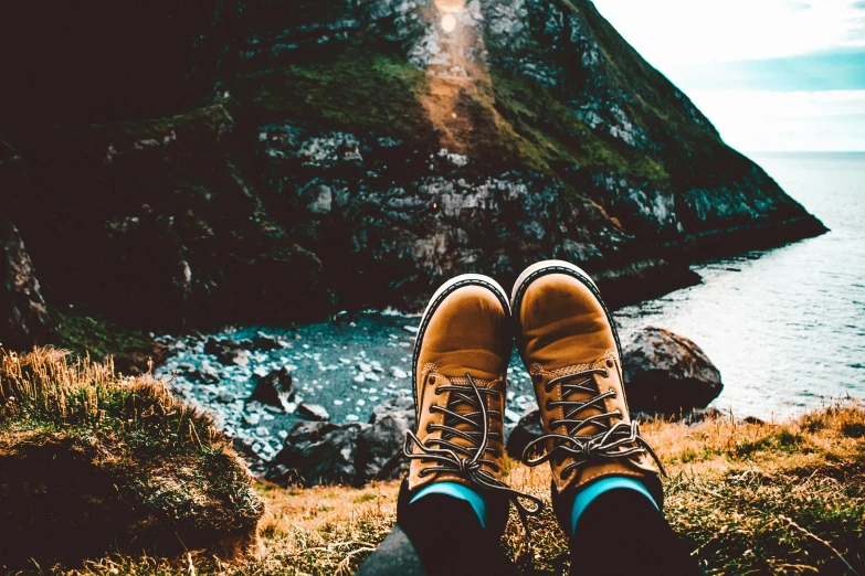 a person sitting on top of a hill next to a body of water, trending on pexels, brown boots, avatar image, selfie photo