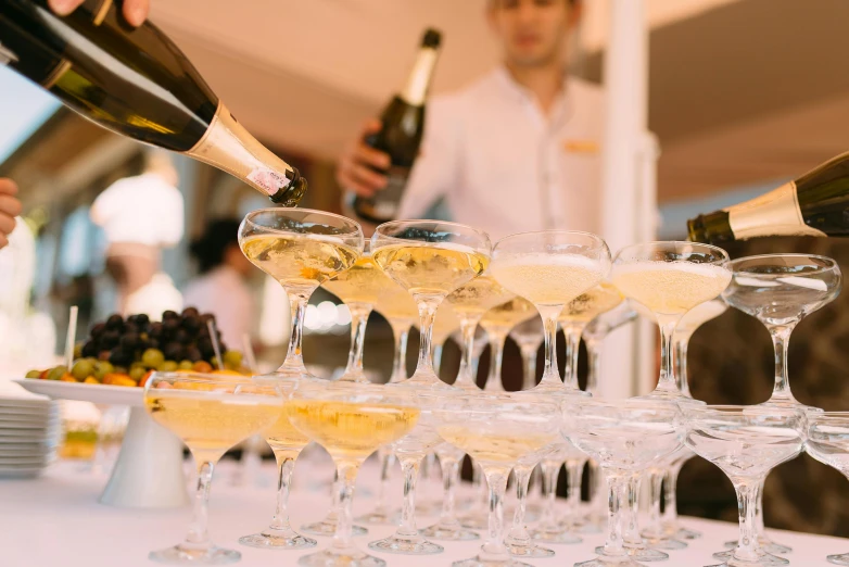 a group of people pouring champagne into wine glasses, by Alexander Fedosav, pexels, white and yellow scheme, al fresco, thumbnail, shades of gold display naturally