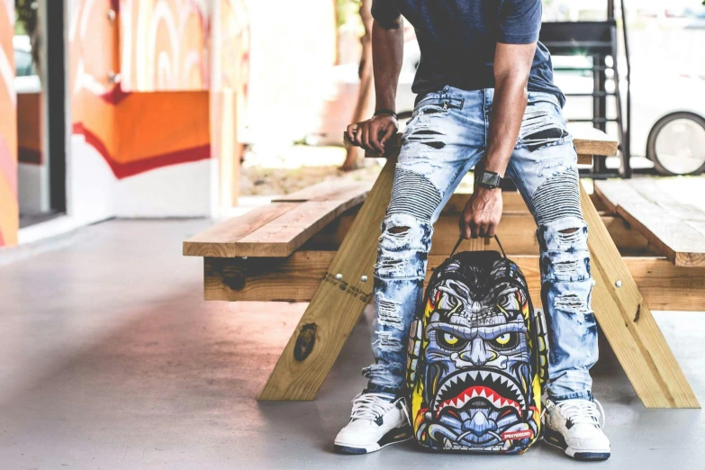 a man sitting on a bench with a backpack, a cartoon, trending on pexels, graffiti, ripped jeans, shark face, strong and ferocious, rapper bling jewelry