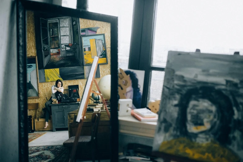 a painting sitting on top of a table next to a mirror, by Julia Pishtar, pexels contest winner, monalisa, inside a grand messy studio, next to a big window, on a yellow canva