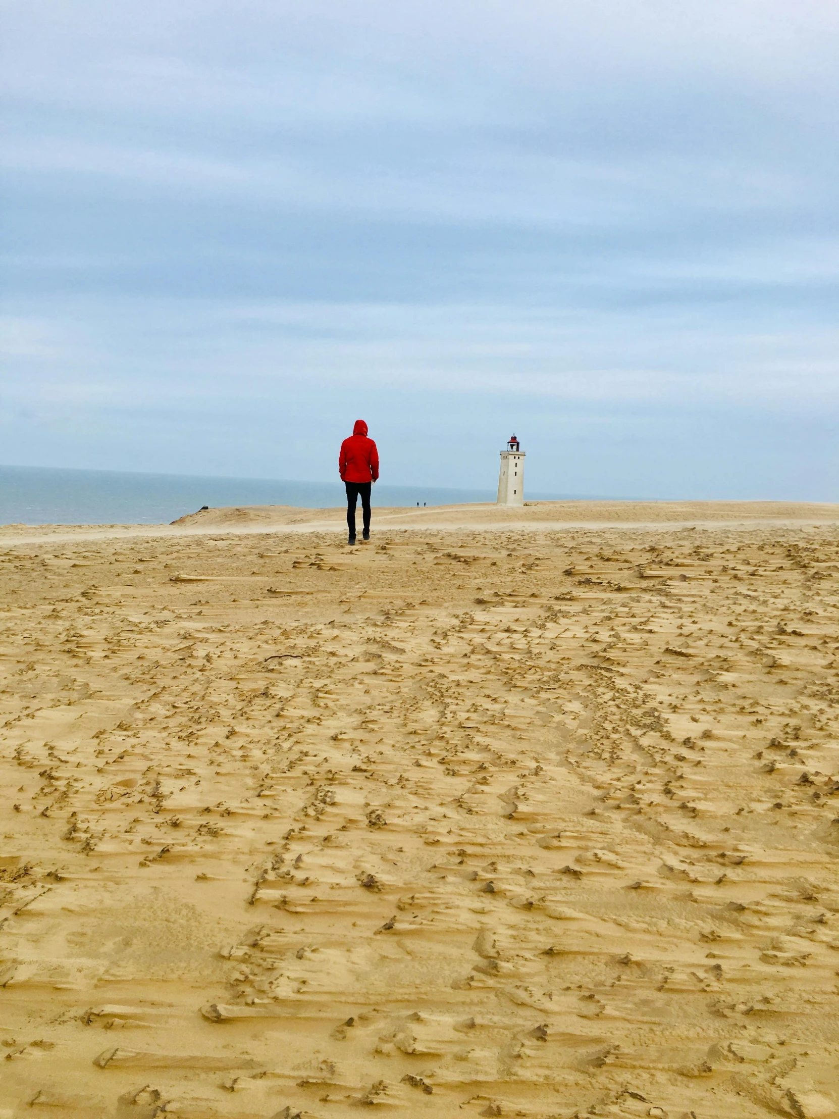 a person standing on top of a sandy beach, inspired by Storm Thorgerson, pexels contest winner, land art, northern france, looking off into the distance, light house, view(full body + zoomed out)