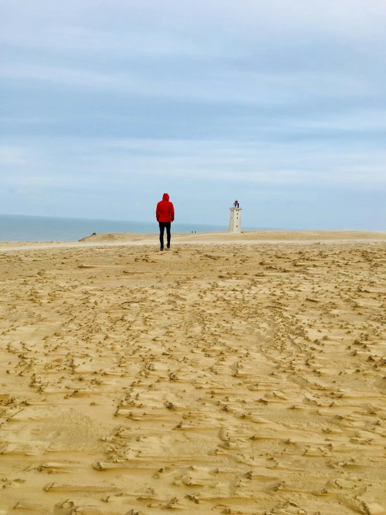 a person standing on top of a sandy beach, inspired by Storm Thorgerson, pexels contest winner, land art, northern france, looking off into the distance, light house, view(full body + zoomed out)