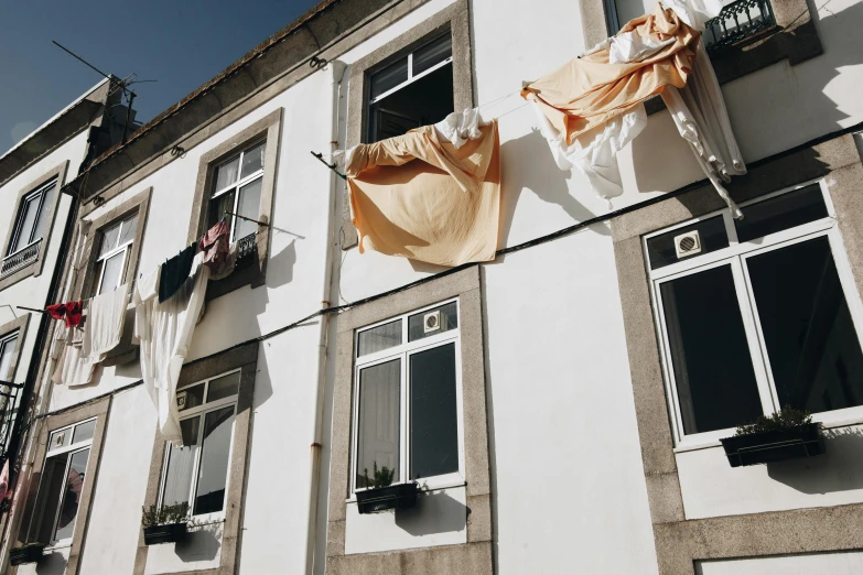 a building with clothes hanging out of the windows, by Matija Jama, pexels contest winner, white and gold robes, gui guimaraes, thumbnail, cloth banners