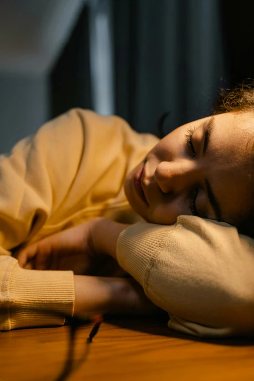 a woman laying on top of a wooden table, inspired by Elsa Bleda, pexels, hurufiyya, he holds her while she sleeps, concerned expression, early evening, teenage girl