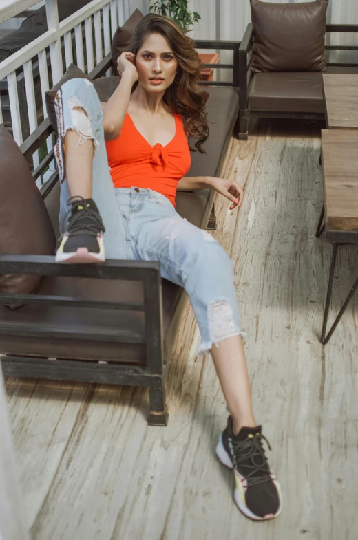 a woman sitting on top of a wooden bench, ripped jeans, wearing an orange t shirt, sitting in a cafe, nivanh chanthara