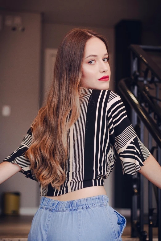 a woman standing in front of a set of stairs, inspired by Ksenia Milicevic, pexels contest winner, wearing stripe shirt, flowing hair, wearing a crop top, sansa